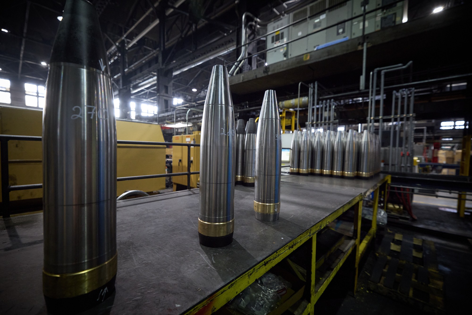 Precision-machined large-caliber artillery shell casings on the floor of an active ammunition production plant